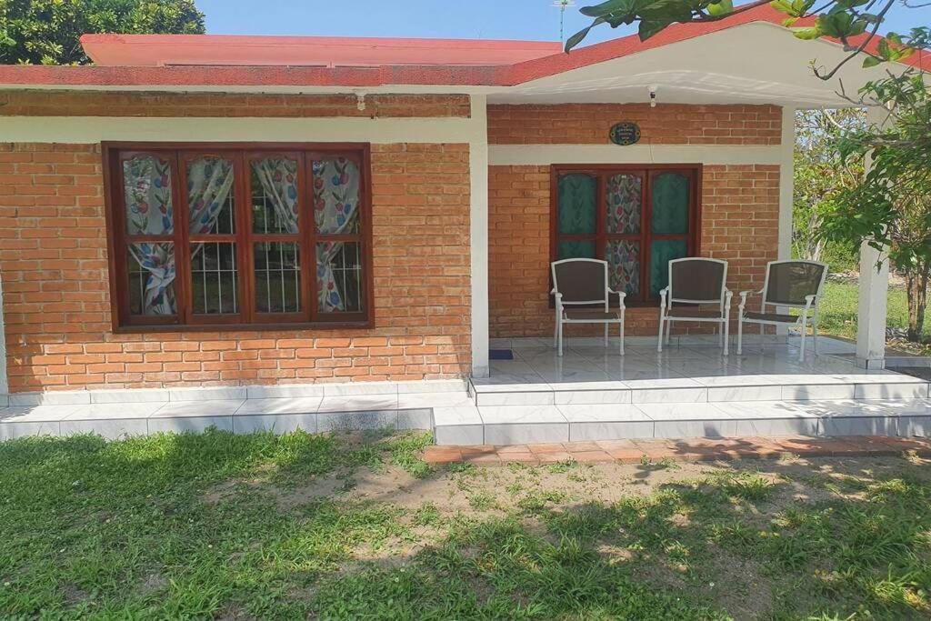 una pequeña casa de ladrillo con sillas en el patio en CASA TULIPANES, CASITAS-TECOLUTLA,CASA DE PLAYA COMPLETA, en Costa Esmeralda