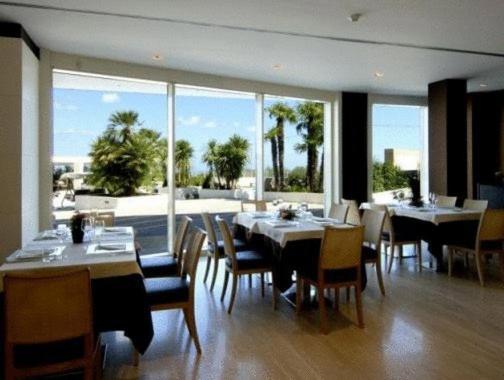 jadalnia ze stołami i krzesłami oraz dużym oknem w obiekcie Hotel Pineta Wellness & Spa w mieście Ruvo di Puglia
