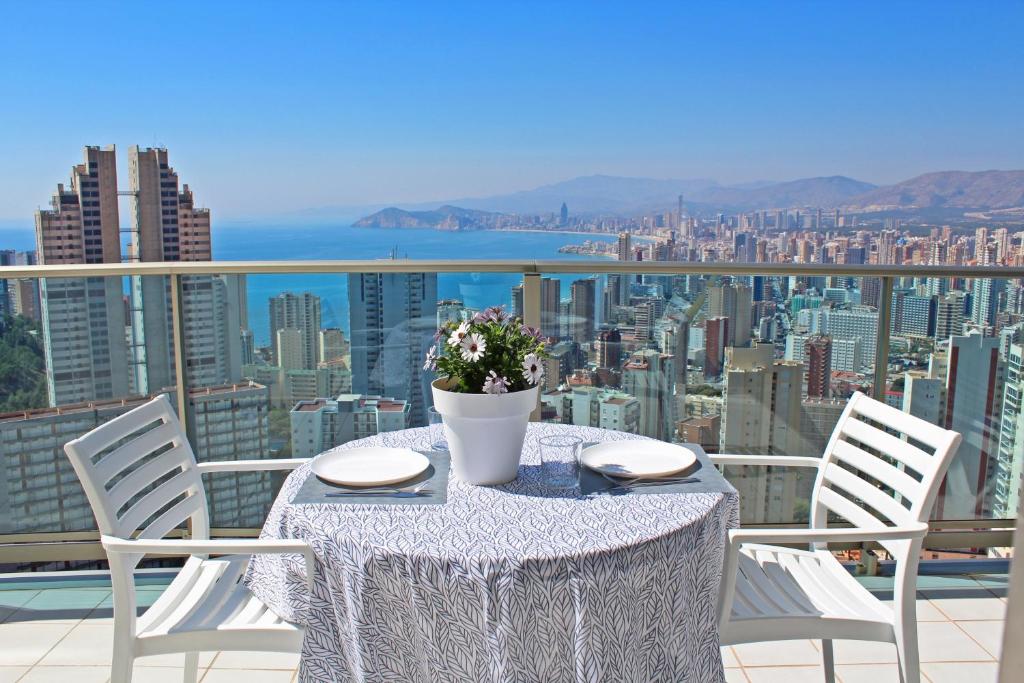 einen Tisch mit einer Blumenvase auf dem Balkon in der Unterkunft Apartamento de Lujo con terraza privada y vistas al mar en Torre Lúgano in Benidorm