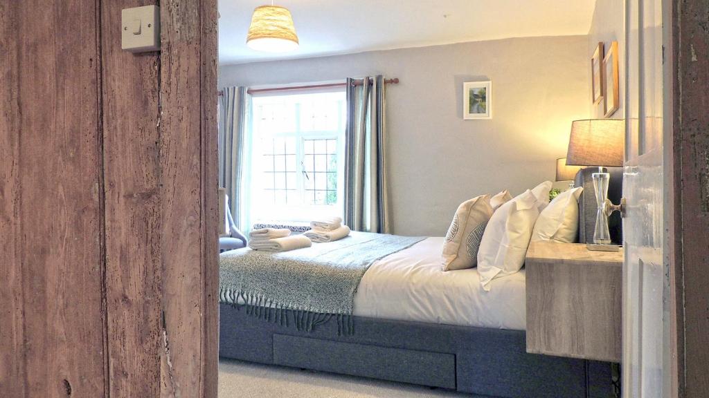 a bedroom with a bed and a window at Magnolia Cottage in Moreton in Marsh
