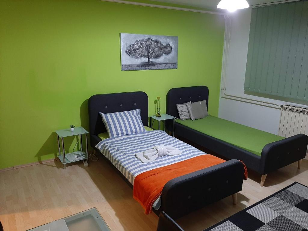 1 dormitorio con 1 cama y 1 cama y paredes verdes en Apartmani Arena Zagreb, en Zagreb