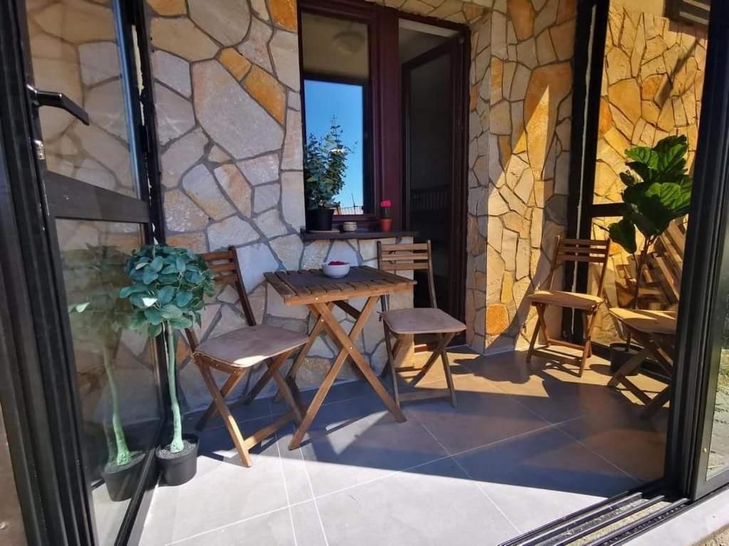 a patio with a table and chairs and a stone wall at Studio Jolly Kop Jana 2 in Kopaonik