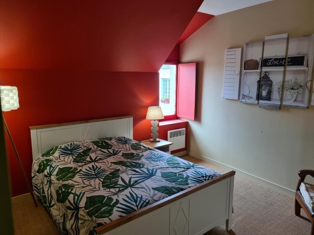 une chambre avec un lit et un mur rouge dans l'établissement Le gîte des Serres, à Parné-sur-Roc