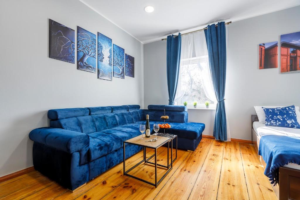 ein Wohnzimmer mit einem blauen Sofa und einem Tisch in der Unterkunft Chopin Park Apartments in Posen