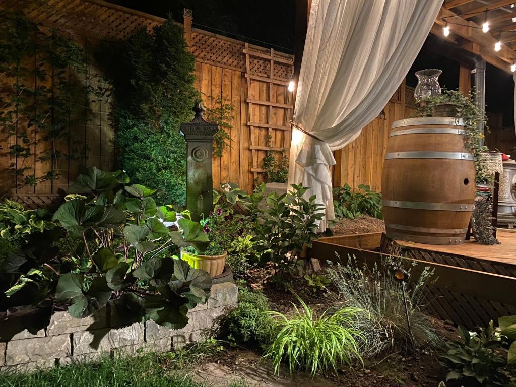 a garden with a barrel and a curtain and plants at Darlington House Bed and Breakfast in Niagara-on-the-Lake