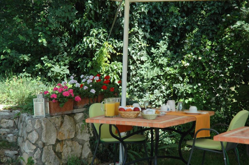 a table and chairs under an umbrella in a garden at Montericco B&B in Negrar