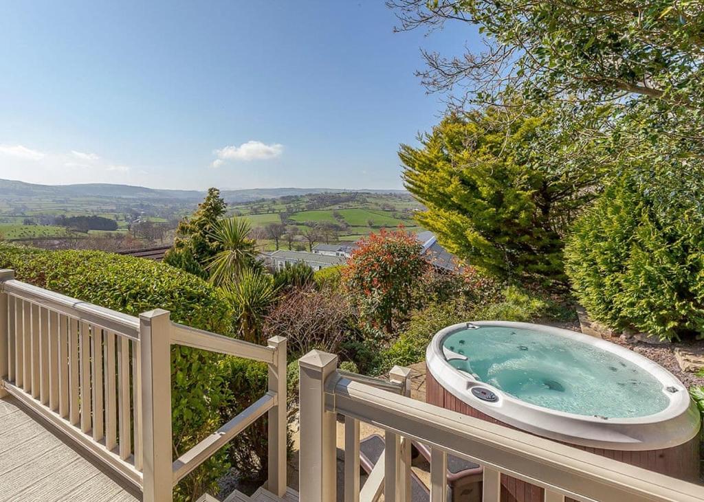 a jacuzzi tub sitting on a wooden balcony at Tan Rallt Holiday Park & Spa in Abergele