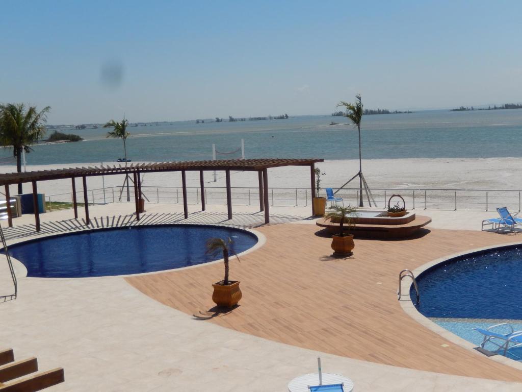 a resort with two swimming pools and a beach at Flat entre mar e lagoa II in Arraial do Cabo