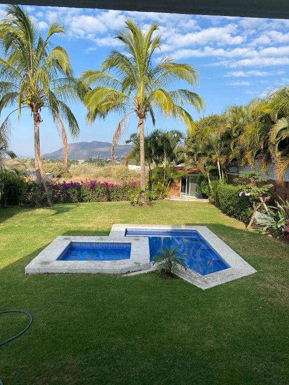 a swimming pool in a yard with palm trees at Casa de las Palmeras Lomas de Cocoyoc in Atlatlahucan