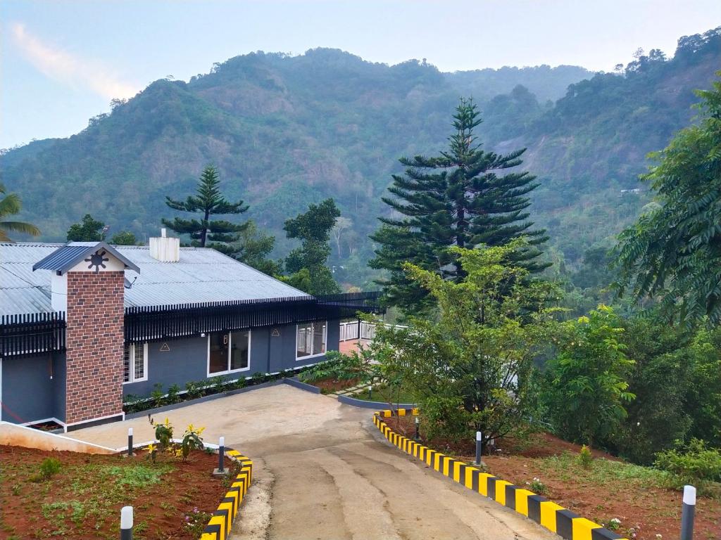 a house on a road with mountains in the background at Riviera inn resort in Chillithodu