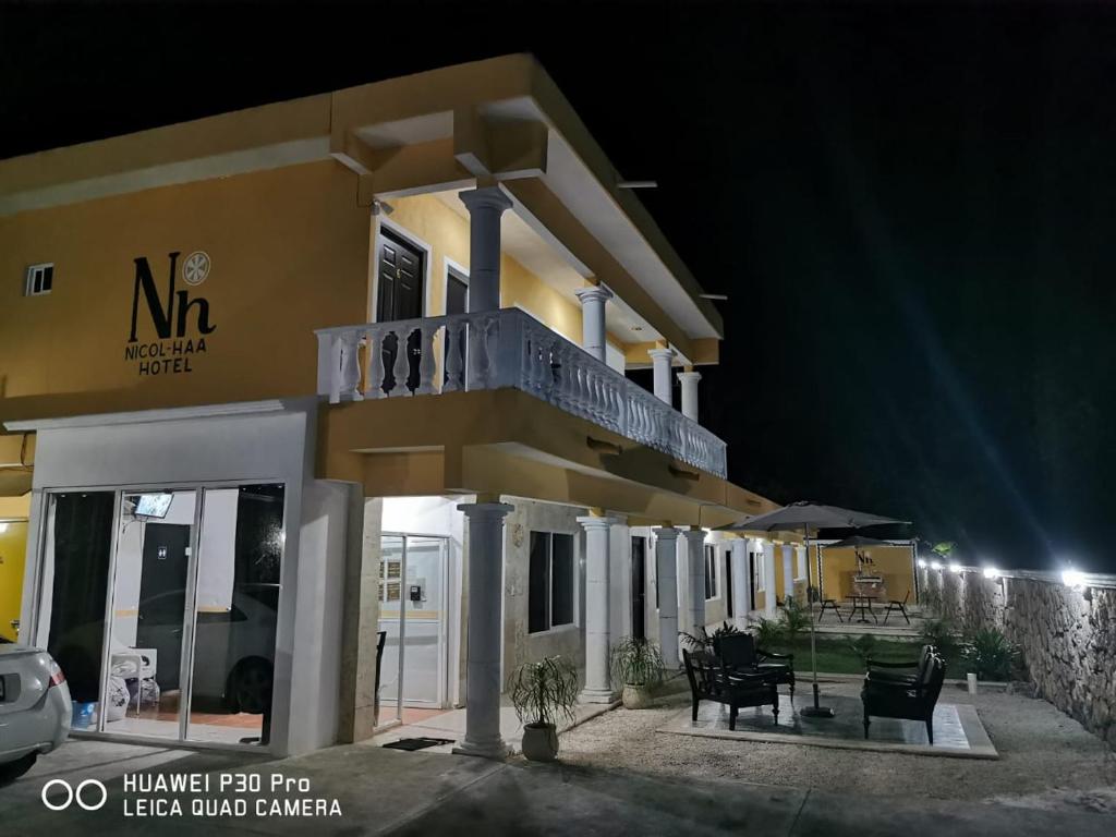 Un grand bâtiment jaune avec balcon est disponible la nuit. dans l'établissement Nicol-Haa, à Izamal