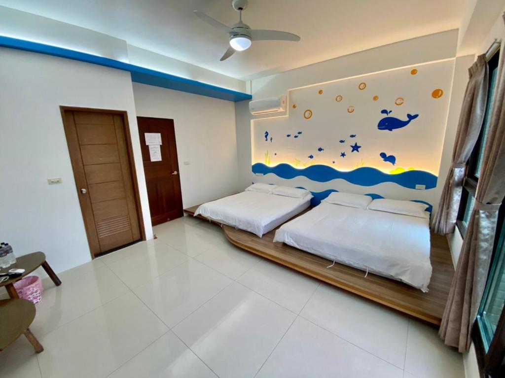 a bedroom with two beds and a painting on the wall at 艷陽天民宿 in Toucheng