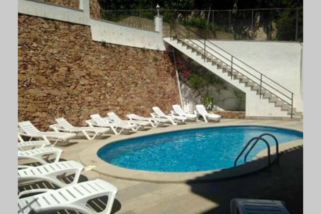 a swimming pool with lounge chairs and a bunch ofitures at Apartamento con piscina en el centro de Blanes in Blanes