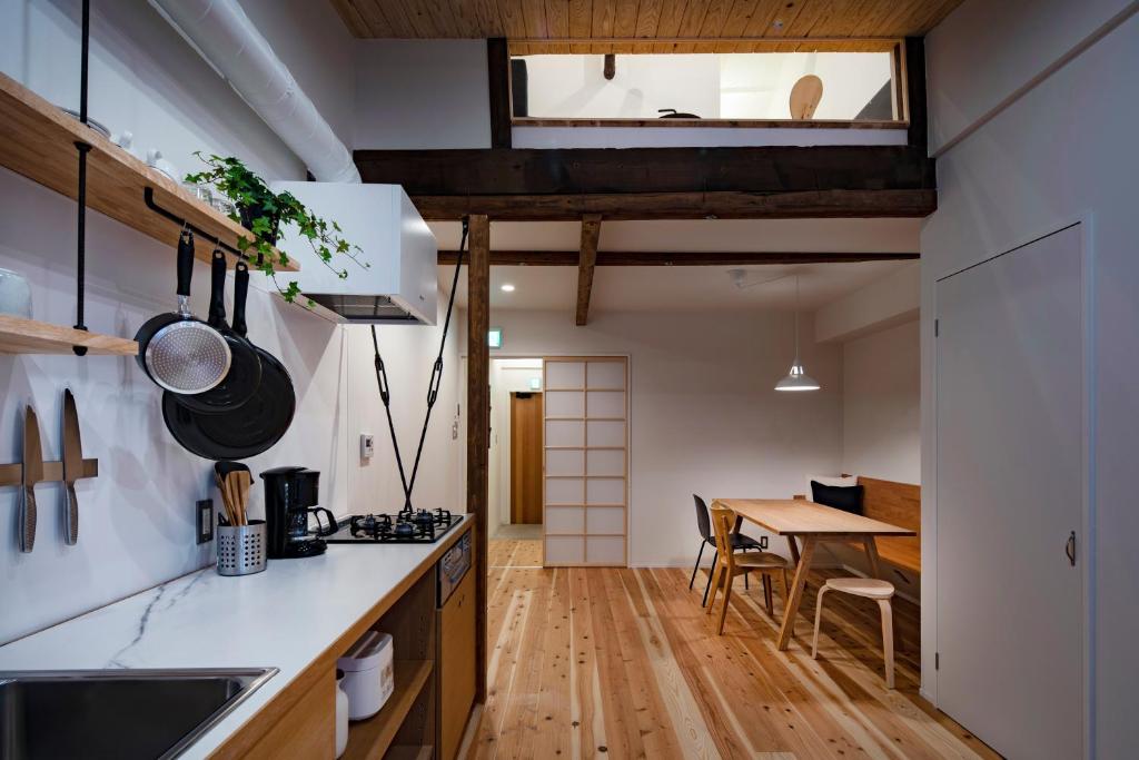 una cucina con banconi bianchi e un tavolo in una stanza di Japan Sessions KANZAKI 02 ad Osaka