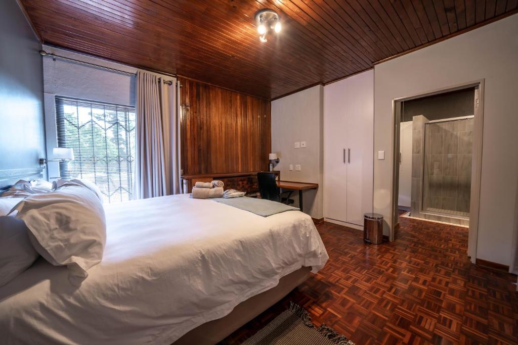 a bedroom with a large white bed and a window at The Haystack on Cowley in Johannesburg