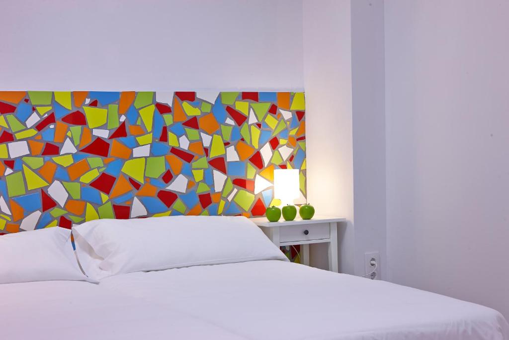 sypialnia z łóżkiem z kolorowym zagłówkiem w obiekcie Pil Pil Hostel Bilbao w mieście Bilbao