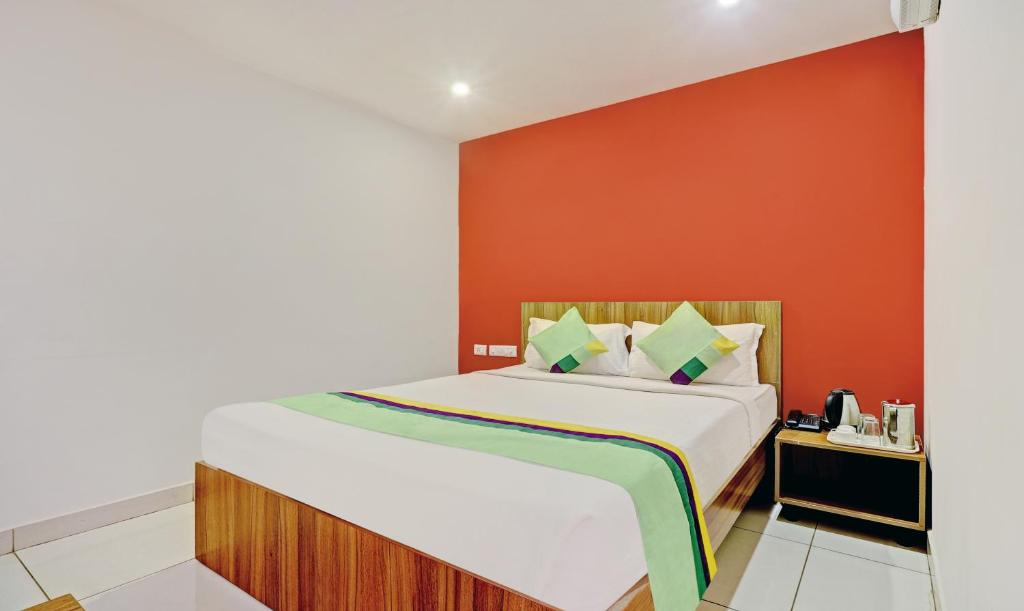 a bedroom with a large bed with an orange wall at Treebo Trend Sai Suites Inn Nagavara in Bangalore