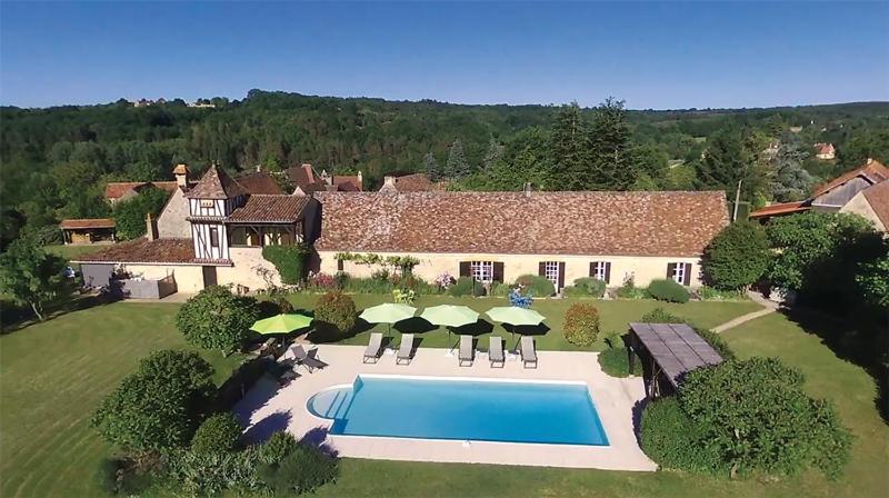 una vista aérea de una casa con piscina y sombrillas en La Ferme de l'Embellie Gîtes et Chambres d'Hôtes, en Le Buisson de Cadouin