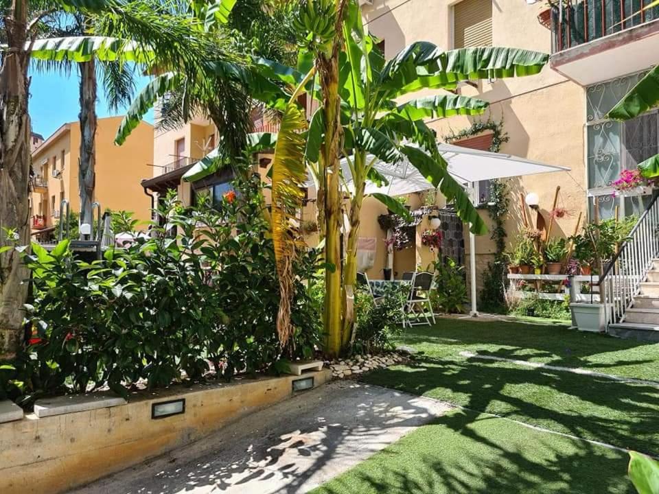 a courtyard with palm trees and a building at Casa Le Rose in Palermo