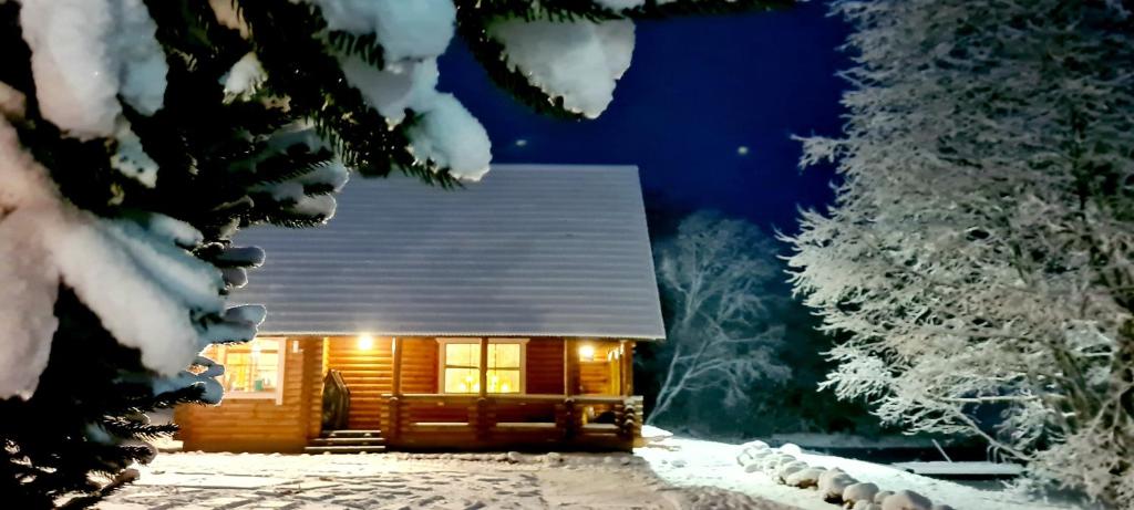 ein Blockhaus im Schnee in der Nacht in der Unterkunft Lombi Holiday House in Otepää