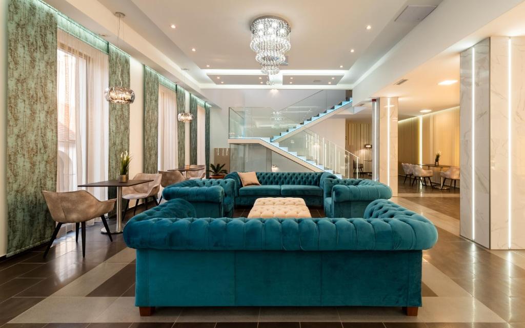 a living room with a blue couch and a table at Fibula Residence Hotel & Wellness - Adults Only in Pécs