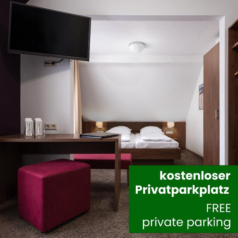 een kamer met een bureau en een bed met een televisie bij Boutique Hotel Societe in Baden-Baden