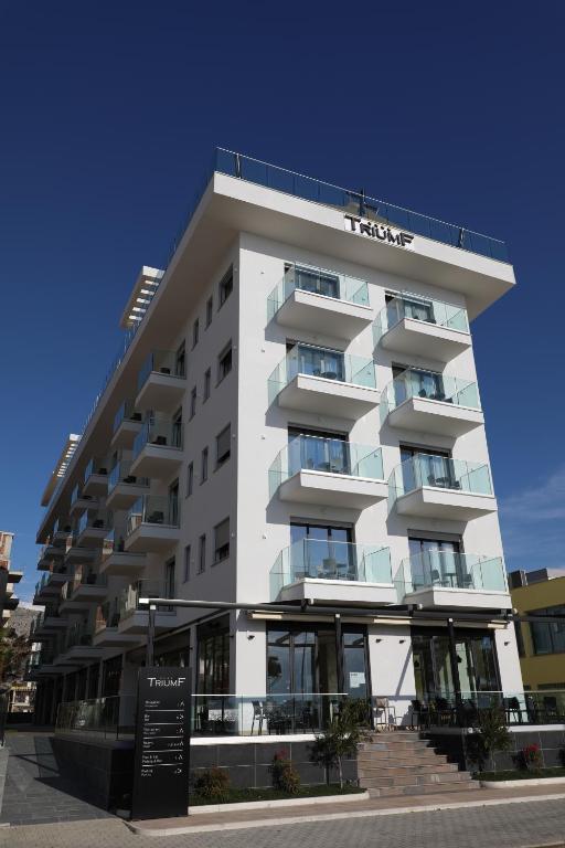 a white building with a sign in front of it at Hotel Triumf Shengjin in Shëngjin