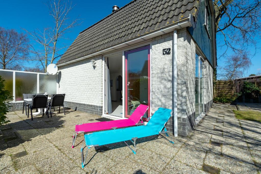a house with a blue and pink couch on a patio at Campanula 52- Sint Maartenszee in Sint Maartensvlotbrug