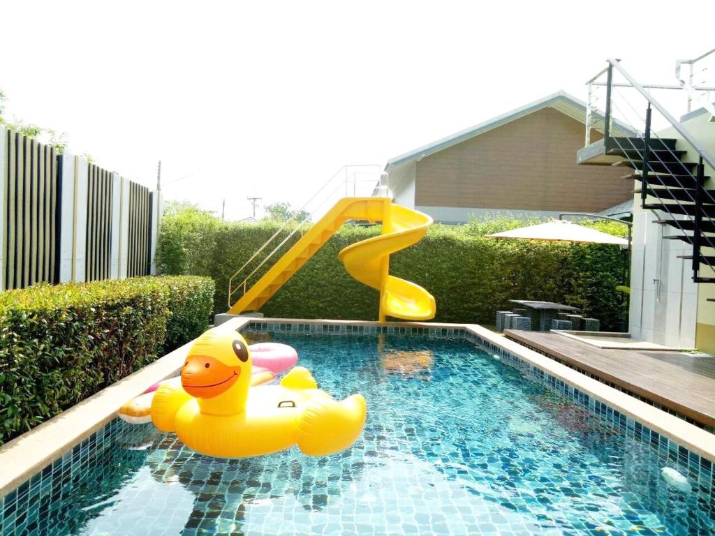 Una piscina con un tobogán amarillo y un patito de goma. en Thacha Pool Villa A, en Hua Hin