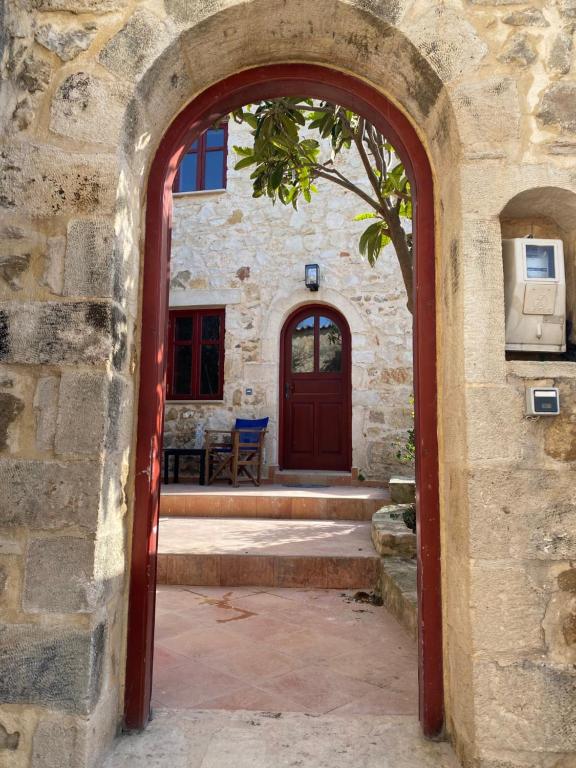 an archway entrance to a stone building with a red door at La Perla de Maroulas in Maroulás