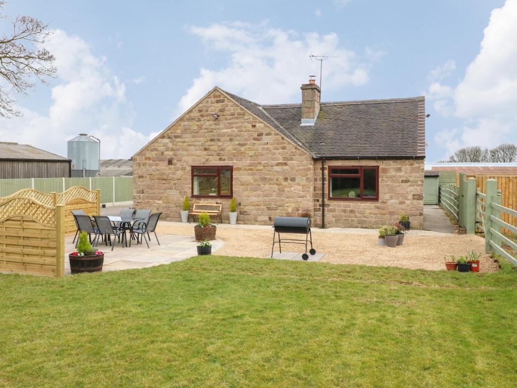 une maison en pierre avec une terrasse et une pelouse dans l'établissement The Lodge, à Belper