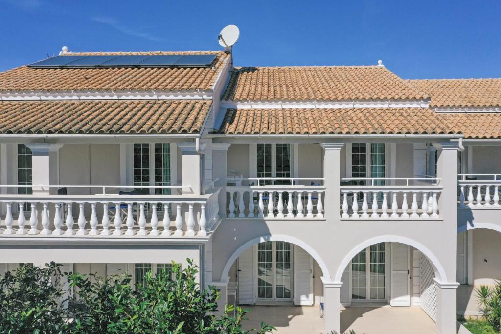 Großes weißes Haus mit Balkon in der Unterkunft Lea Family Resort in Kassiopi