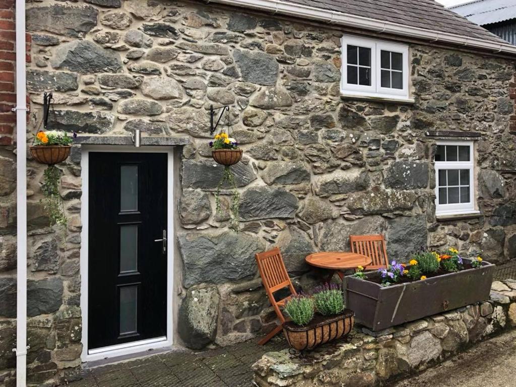 a stone house with two chairs and a table in front of it at The Grooms Cottage in Llanrug