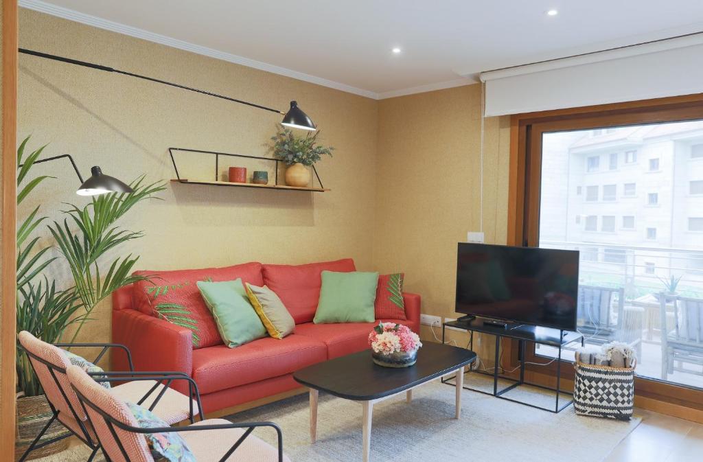 un soggiorno con divano rosso e TV di P18 Villalia Apartamento en la Isla de la Toja a Isla de la Toja