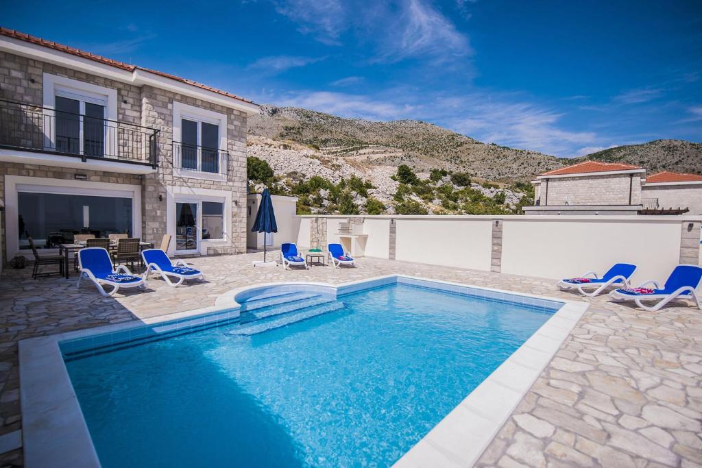 IvanicaにあるLuxury Villa Layla with private pool near Dubrovnikの椅子と家のあるプール