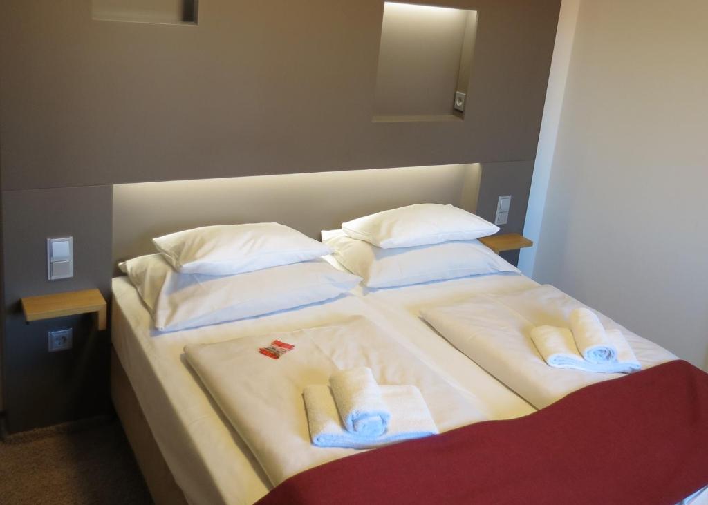 a bed with a white comforter and pillows at Hotel Neuthor in Ulm