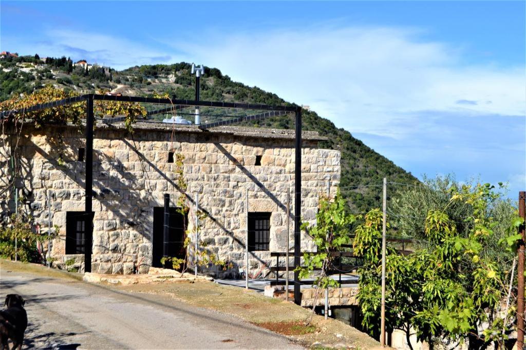 a large stone building with a door on a hill at Beit el Deif in Jbeil