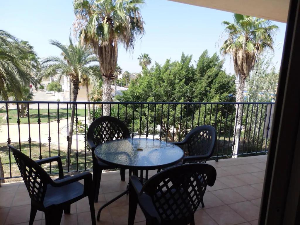 d'une table et de chaises sur un balcon avec des palmiers. dans l'établissement Nice apartment with spacious terrass and rooftop, à Los Alcázares