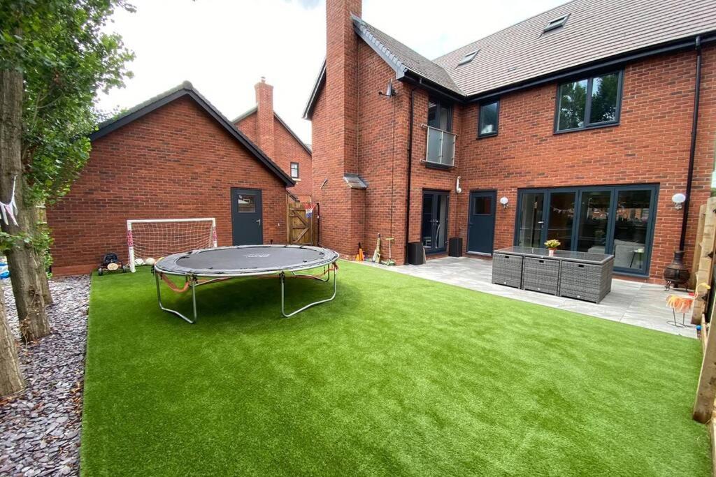 einen grünen Hof mit einem Tisch vor einem Gebäude in der Unterkunft Exclusive 5 Bed Family House in Village Location in Sheepy