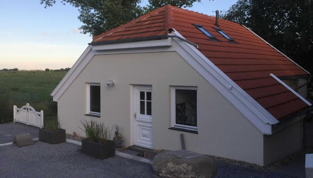 een klein wit gebouw met een rood dak bij Ferienhaus Kaept n Poldi 25192 in Bunde