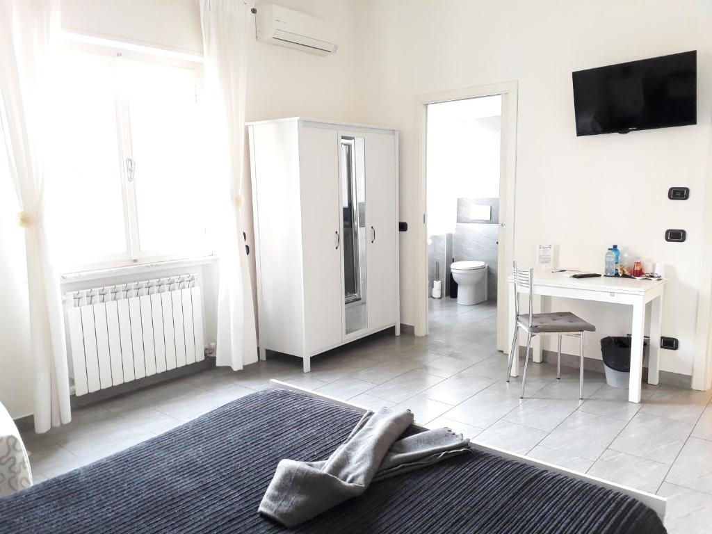 a white room with a bed and a table and a desk at Affittacamere Delfo in Pisa