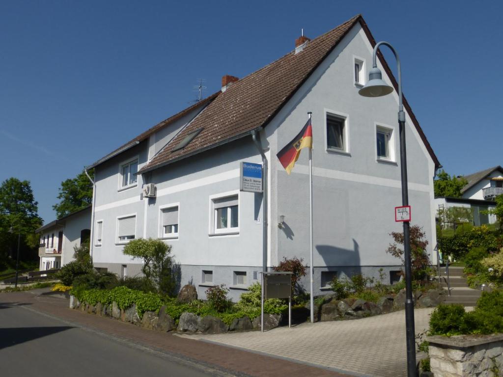 un edificio blanco con banderas delante en Ferienwohnung Steimer, en Langgöns