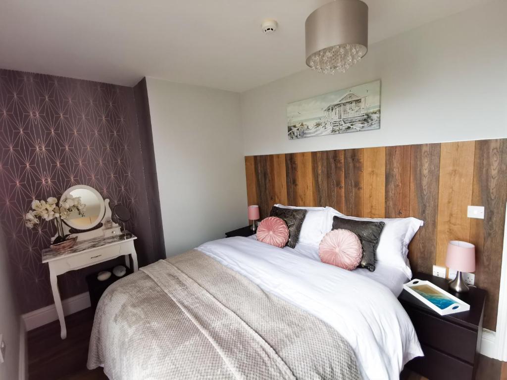 1 dormitorio con 1 cama grande y cabecero de madera en Sunrise View 2 Bed Apartment Sleeps 4 Spa Bath, en Bridlington