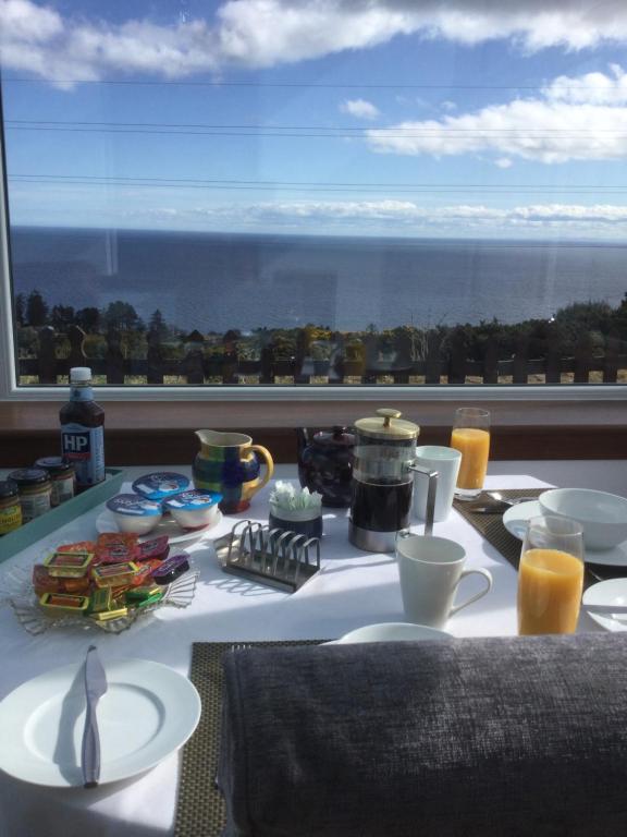 a table with food and a view of the ocean at Piper's Cave bed and breakfast in Helmsdale