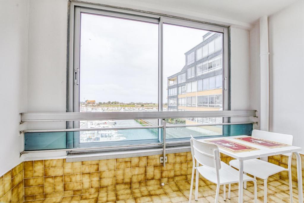 a balcony with a table and chairs and a large window at Le Gréement - Appt vue sur le port in Courseulles-sur-Mer