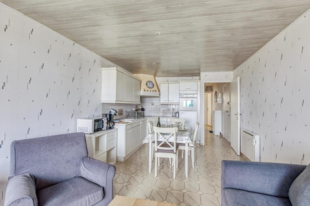 a kitchen with two couches and a table in a room at Le Gréement - Appt vue sur le port in Courseulles-sur-Mer