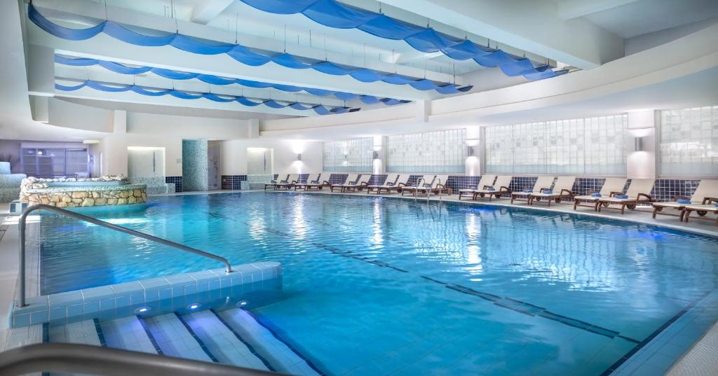 a large swimming pool with chairs in a building at Valamar Diamant Hotel in Poreč