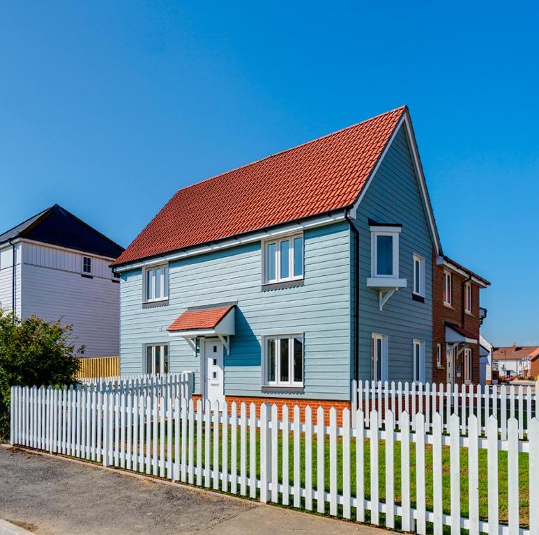 a blue house behind a white picket fence at Kittiwake Cottage Camber Sands in Camber