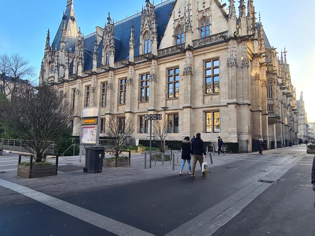dos personas caminando frente a un gran edificio en Rouen hyper centre ville Palais de Justice, en Rouen