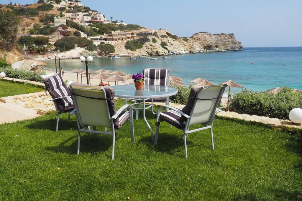 a table and chairs sitting on the grass near the ocean at Dreamwave Residence - Unique holidays by the sea in Lygaria